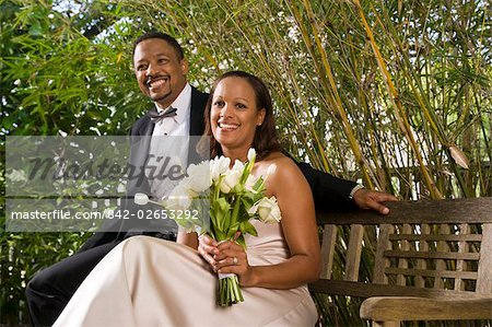 Portrait Of Happy African American Bride And Groom Sitting Outside