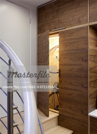 Open walnut storage cupboard on stairs with stored bicycle. Architects: WE Design - Winston Ely