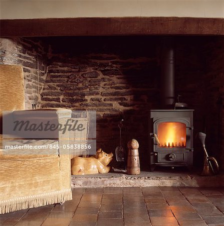 Upholstered sofa in front of woodburning stove in inglenook fireplace