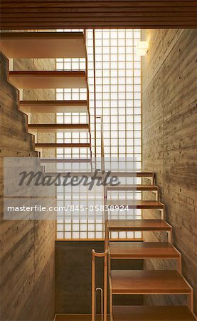 Contemporary wooden staircase in front of tall window