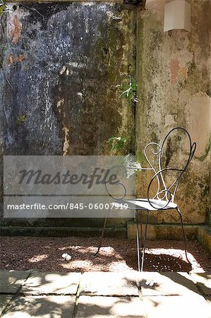 Metal chair in courtyard garden, Lunuganga, Sri Lanka. Country home of the late Geoffrey Bawa now a boutique hotel. Architects: Geoffrey Bawa