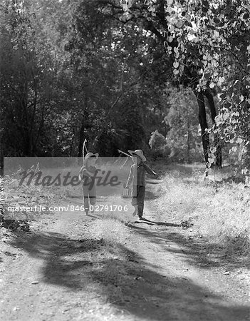 1940s 1950s TWO BOYS IN DUNGAREES PLAID SHIRTS STRAW HATS WALKING DOWN DIRT ROAD CARRYING FISHING POLES & CAN OF BAIT