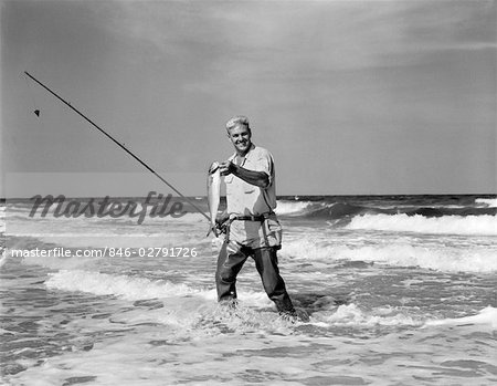 1950s OLDER MAN STANDING IN SURF IN WADERS HOLDING FISH IN ONE HAND FISHING  POLE IN OTHER - Stock Photo - Masterfile - Rights-Managed, Artist:  ClassicStock, Code: 846-02791726