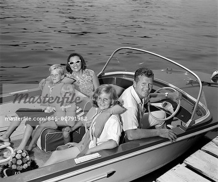 1960s SMILING FAMILY OF FIVE IN DOCKED BOAT CHILDREN WEARING LIFE VESTS