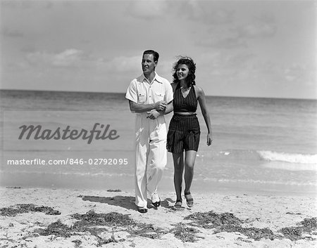 1930s Couple Arm In Arm Walking Up From Ocean Smiling Man In White Shirt Slacks Woman In Dark Halter Top Shorts Stock Photo Masterfile Rights Managed Artist Classicstock