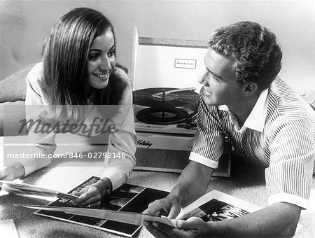 1960s TEEN COUPLE PLAYING LP VINYL RECORDS ON PORTABLE PHONOGRAPH 1960s TEEN COUPLE PLAYING LP VINYL RECORDS ON PORTABLE PHONOGRAPH