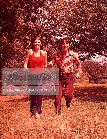 1960s YOUNG COUPLE RUNNING IN FIELD