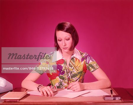 1970s WOMAN AT DESK WEARING COLORFUL BLOUSE