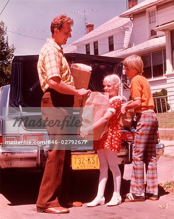 1970s FATHER AND CHILDREN UNLOADING GROCERIES FROM CAR