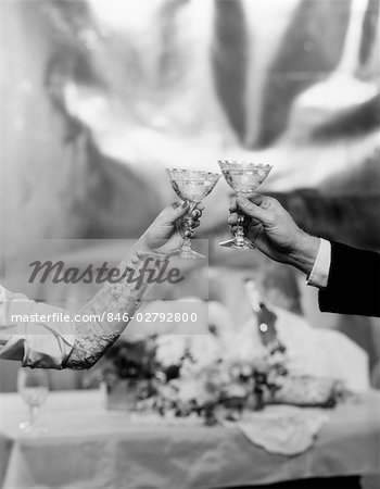 HANDS & ARMS OF A BRIDE AND GROOM TOASTING WITH CHAMPAGNE GLASSES
