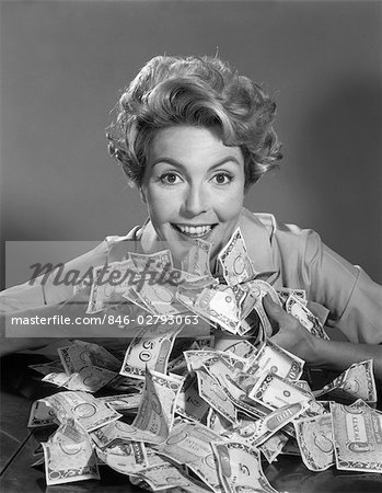 1950s 1960s SMILING WOMAN SCOOPING UP PILE OF MONEY BILLS CASH