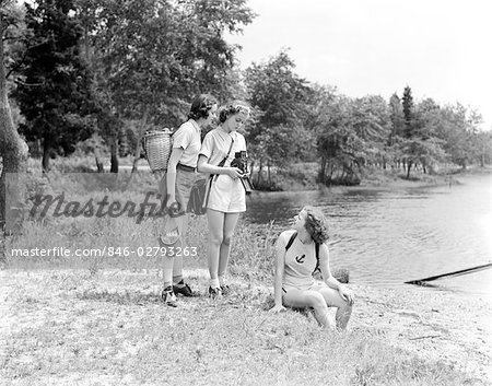 THREE YOUNG LADIES WOMEN WOODS LAKE SITTING NATURE CAMERA PHOTOGRAPHER - Stock - Masterfile - Rights-Managed, Artist: Code: 846-02793263