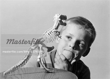 1960s BLOND BOY HAND ON CHIN LOOKING AT SKELETON MODEL OF DINOSAUR TYRANNOSAURUS REX