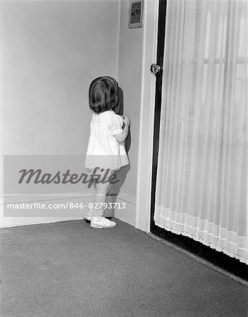1950s LITTLE GIRL IN WHITE DRESS BEING PUNISHED STANDING IN A CORNER DISCIPLINE PUNISHMENT BEHAVIOR PARENTING
