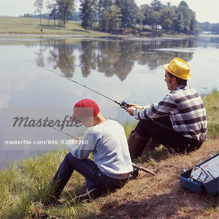 A man kneeling down next to a woman holding a fishing pole photo