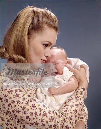 1960s CLOSE-UP OF MOTHER HOLDING CRYING BABY INFANT WOMAN FUSSING PROFILE CUDDLING