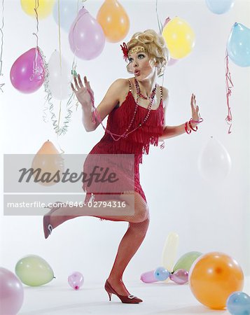 1970s WOMAN RED FRINGE 1920s FLAPPER DRESS DANCING CHARLESTON AMONG PARTY BALLOONS STREAMERS