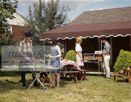 1960s TWO TEENAGED COUPLES HAVING BARBECUE IN SUBURBAN BACKYARD