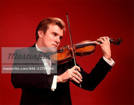 1960s 1970s MAN TUXEDO PLAYING VIOLIN VIOLINIST MUSICIAN RED BACKGROUND