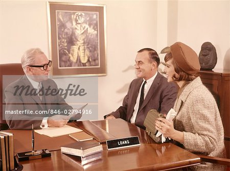 1960s MAN BANK LOAN OFFICER INTERVIEWING COUPLE MAN WOMAN AT DESK IN MORTGAGE FINANCE OFFICE