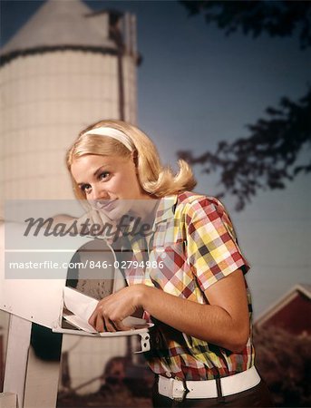 1960s THOUGHTFUL BLOND WOMAN RURAL DELIVERY MAILBOX FARM BACKGROUND PUTTING LETTER IN TAKE OUT MAIL BOX