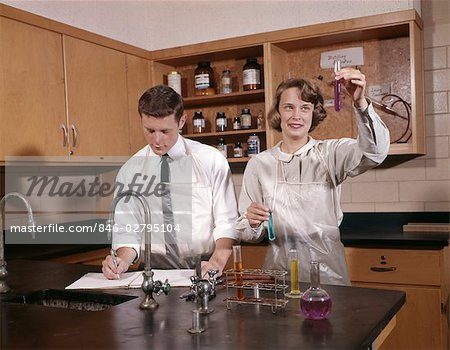 1960s GIRL AND BOY COLLEGE STUDENTS IN SCIENCE LAB