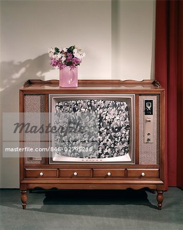 1960s LARGE CONSOLE TELEVISION WITH BLACK AND WHITE SCREEN IMAGE AND VASE OF FLOWERS ON TOP NOSTALGIA
