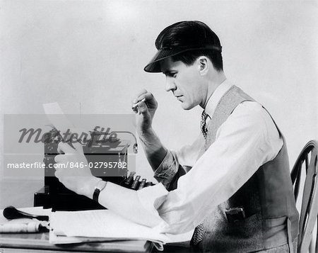 1930s MAN AT THE TYPEWRITER WEARING A VISOR SHIRT TIE AND VEST SMOKING A CIGARETTE WHILE TAKING PAPER FROM THE TYPEWRITER
