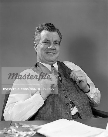 1940s MAN IN SUIT SITTING AT DESK SMILING