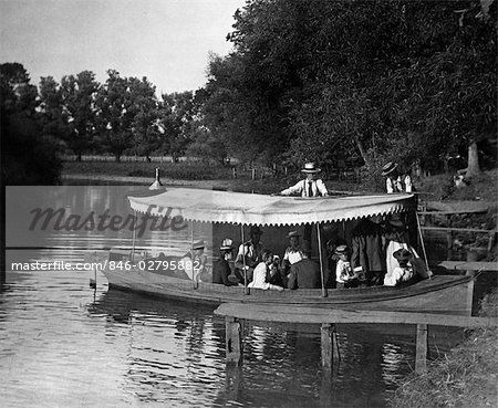 1890s 1900s TURN OF THE CENTURY GROUP IN BOAT WITH CANOPY BEING PUSHED OUT INTO LAKE