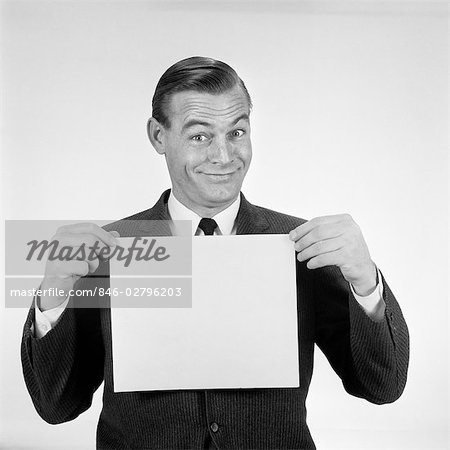 1950s 1960s SMILING MAN FUNNY FACIAL EXPRESSION HOLDING UP BLANK EMPTY PLACARD SIGN