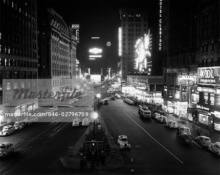 1930s OVERHEAD OF TIMES SQUARE LIT UP AT NIGHT WITH CARS LINING CURBS