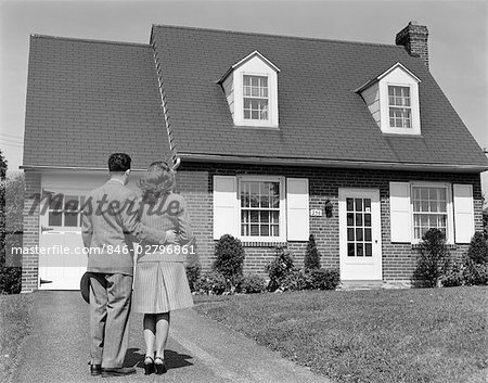 1940s COUPLE LOOKING AT SUBURBAN HOUSE