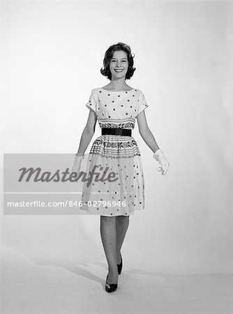 1950s WOMAN STANDING SMILING WEARING DRESS AND GLOVES