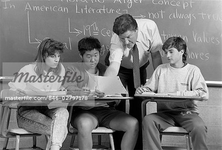 College Students Men Woman Teacher In Classroom Sitting At Desks