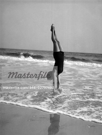 1920s WOMAN IN BATHING SUIT COSTUME STANDING ON BEACH PUTTING BAIT