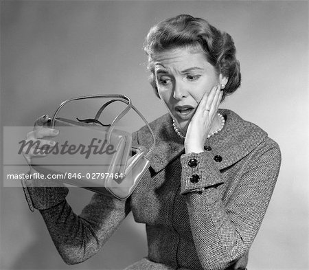 1950s WOMAN WITH EXAGGERATED EXPRESSION HAND ON FACE LOOKING INSIDE HER PURSE
