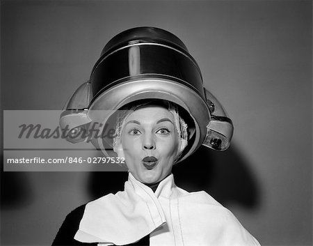 1950s WOMAN UNDER HAIR DRYER WITH TOWEL ON SHOULDERS AND HAIR NET