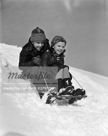 1930s BOY AND GIRL GOING DOWN HILL ON SLED OUTSIDE IN SNOW