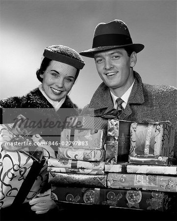 1950s SMILING PORTRAIT COUPLE IN WINTER COATS & HATS HOLDING WRAPPED GIFTS