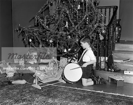 1930s BOY AND GIRL PLAYING WITH PRESENTS BY CHRISTMAS TREE