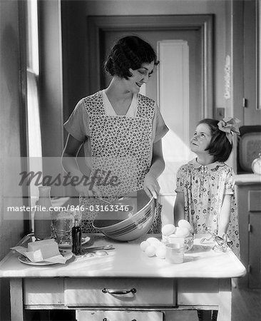 1920s 1930s MOTHER WITH MIXING BOWL IN KITCHEN WITH DAUGHTER