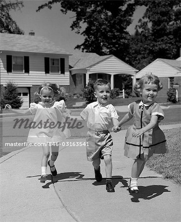 1960s CHILDREN WALKING SKIPPING ON SIDEWALK