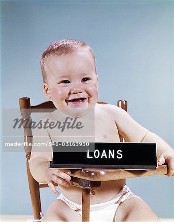 1960s BABY SMILING SITTING HIGH CHAIR WITH BANKING LOANS SIGN