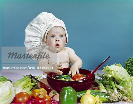 1960s BABY WEARING CHEF HAT ABOUT TO TOSS SALAD WITH HANDS WOODEN SALAD BOWL FRESH VEGETABLES INGREDIENTS