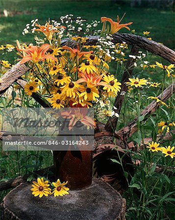 SUMMER WILDFLOWER BOUQUET OUTDOORS ON TREE STUMP BY WAGON WHEEL