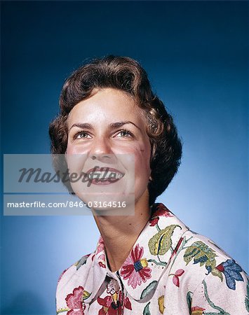 1960s SMILING WOMAN IN WHITE PRINT DRESS LOOKING UP STUDIO