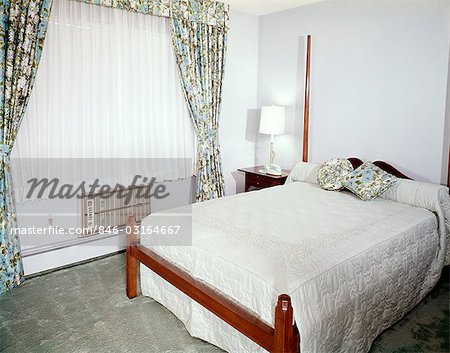 1960s BEDROOM WITH FULL SIZE BED WINDOW WITH FLORAL PRINT DRAPES SHEERS AND AIR CONDITIONER