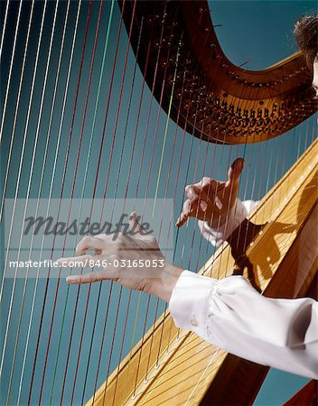 1960s CLOSE UP OF WOMAN'S HANDS PLAYING HARP PLUCKING STRINGS