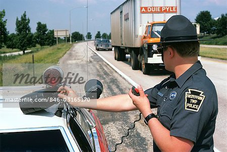 1970s POLICE OFFICER MAN OPERATING RADAR EQUIPMENT ROADSIDE CHECK FOR SPEEDING TRAFFIC